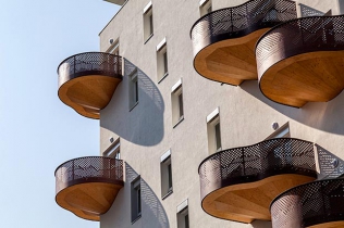 Drewniane balkony na białej elewacji